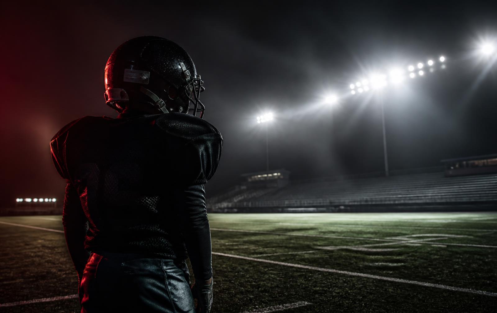 Youth football player under stadium lights